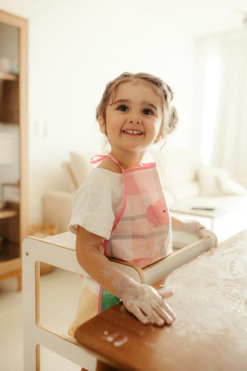 Happy child with apron baking cookies in a sunny kitchen, full of joy and energy.